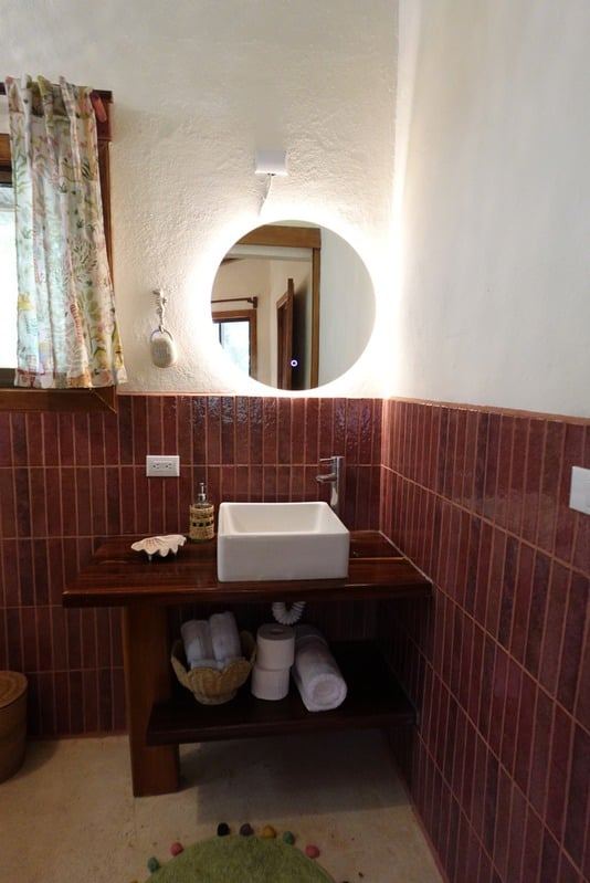 Bathroom with terracotta tiles and a round mirror