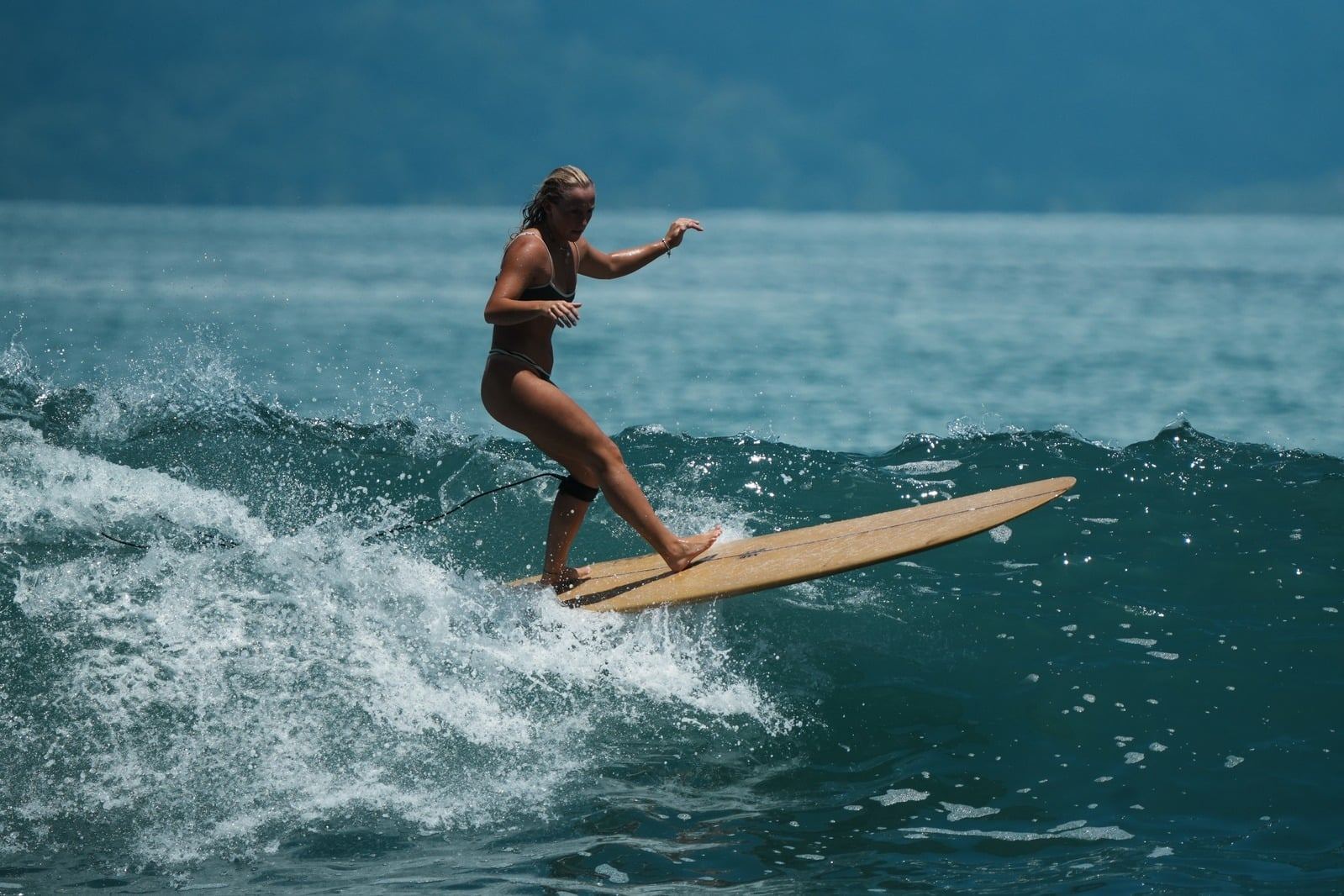 Surfer walking to the nose of a longboard on a clean green wave